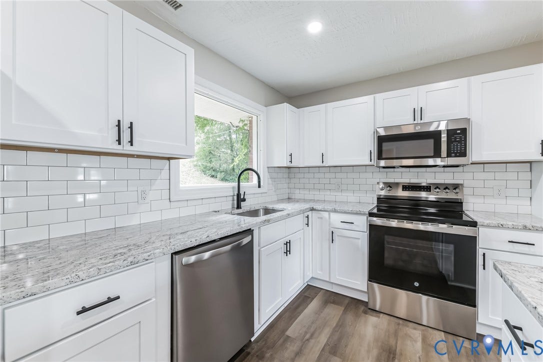 White cabinetry, subway tile backsplash, stainless steel appliances, granite countertops, and wood-finish flooring
