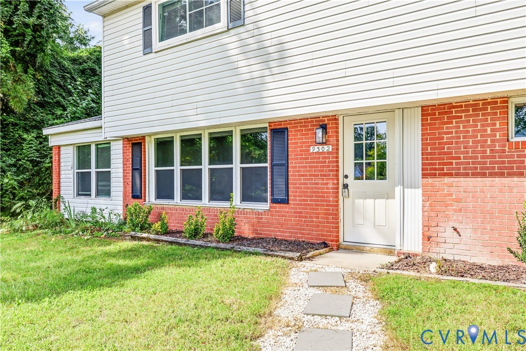 Brick and siding exterior featuring multiple windows with dark shutters