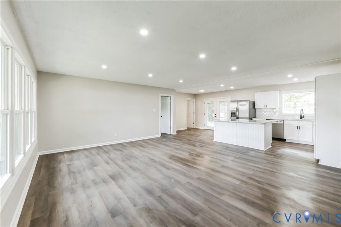Open-concept living space featuring wood-finish flooring, recessed lighting, and ample natural light from multiple windows