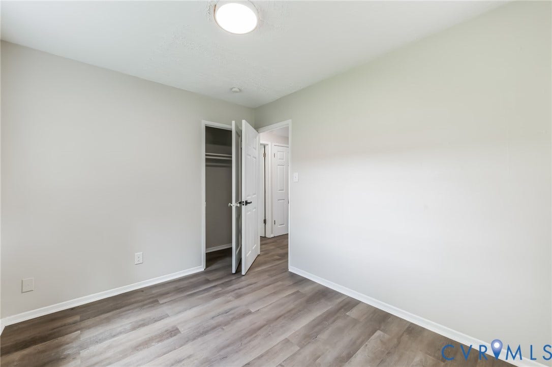 Wood-finish flooring, white painted walls, and a flush mount ceiling light fixture