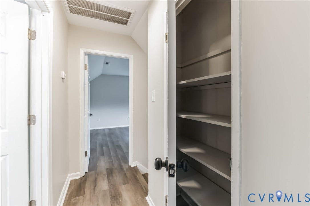 Hallway with wood-finish flooring, white trim, and a built-in shelving unit
