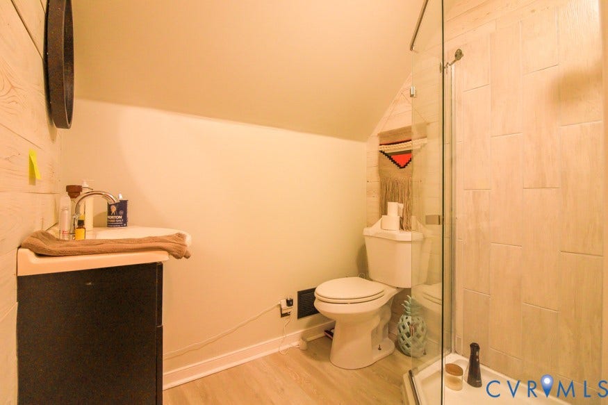 511 Riverview Court, Chester, VA 23836 Built-in vanity with a circular basin sink, a wall-mounted glass shower enclosure, and light wood-finish flooring