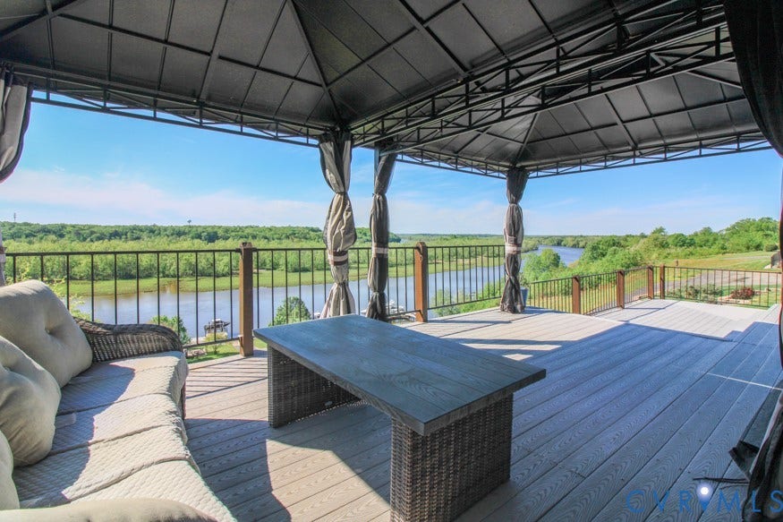 511 Riverview Court, Chester, VA 23836 Expansive outdoor deck featuring a fixed gazebo with privacy drapes, durable composite decking, and metal railings overlooking a natural water feature