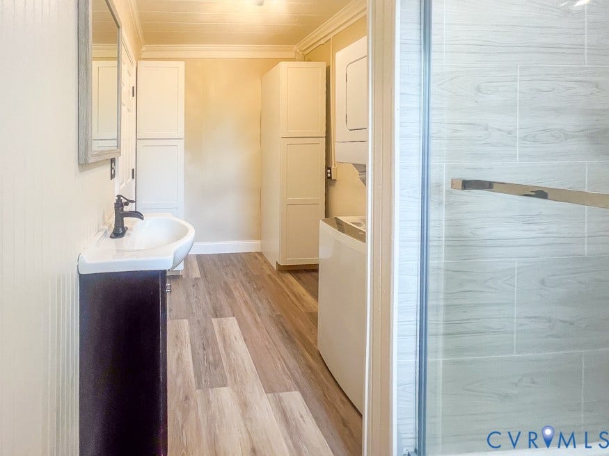 511 Riverview Court, Chester, VA 23836 Vanity with a white vessel sink and dark wood-finish cabinetry, wood-finish flooring, white built-in storage cabinets, and a glass-enclosed shower with tiled walls