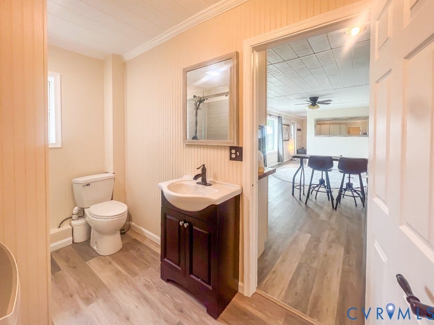 511 Riverview Court, Chester, VA 23836 Bathroom featuring wood-finish flooring, a wood-finish vanity with a white basin, a white toilet, and wainscoting