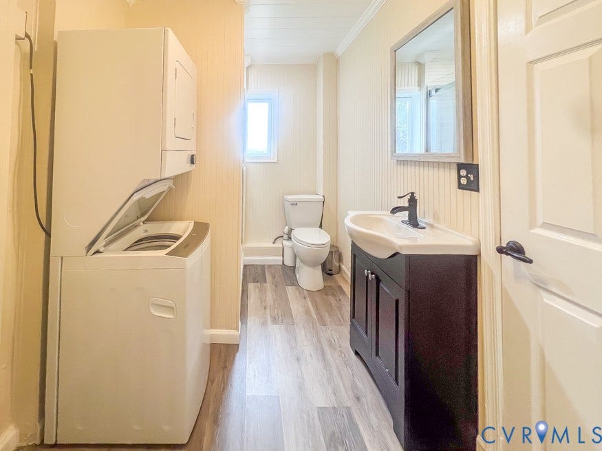 511 Riverview Court, Chester, VA 23836 Stacked washer and dryer unit, wood-finish flooring, dark wood vanity with white sink, matte black faucet, and a rectangular framed mirror