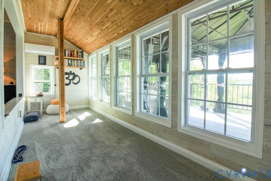 511 Riverview Court, Chester, VA 23836 Wood-paneled vaulted ceiling, built-in shelving, carpet flooring, multiple double-hung windows, and a dedicated wall-mounted air conditioning unit