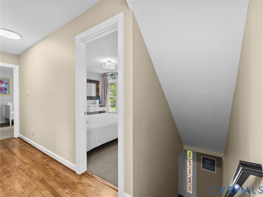 12100 English Ivy Lane, Glen Allen, VA 23059 Hallway featuring wood-finish flooring, white door casing, and a staircase with a built-in vertical window accent