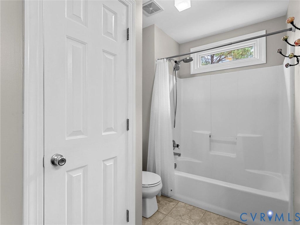 12100 English Ivy Lane, Glen Allen, VA 23059 Bathroom featuring a white tub-and-shower combination, neutral tile flooring, a rectangular transom window, and a paneled interior door
