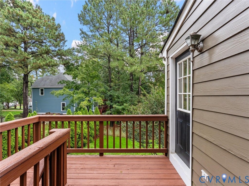 12100 English Ivy Lane, Glen Allen, VA 23059 Exterior deck featuring horizontal wood-finish siding, a wooden railing, a multi-pane glass door, and a wall-mounted outdoor light fixture
