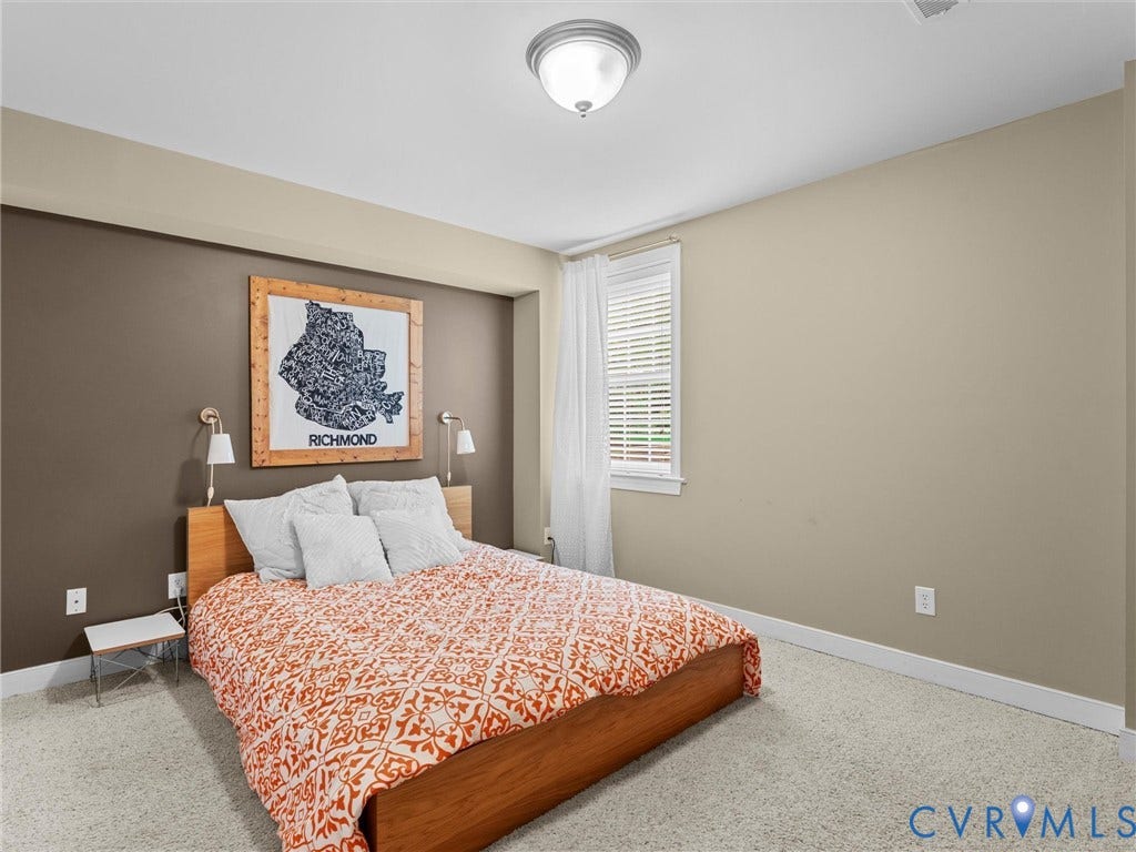 12100 English Ivy Lane, Glen Allen, VA 23059 Neutral-toned bedroom featuring carpeted flooring, two wall-mounted adjustable reading lamps, and a window with white window blinds