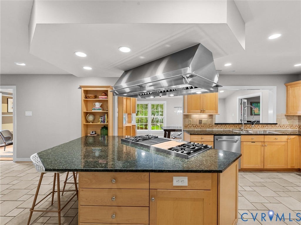 12100 English Ivy Lane, Glen Allen, VA 23059 Kitchen featuring a large central island with an integrated gas cooktop, professional-grade stainless steel range hood, natural wood cabinetry, built-in shelving, and tile flooring