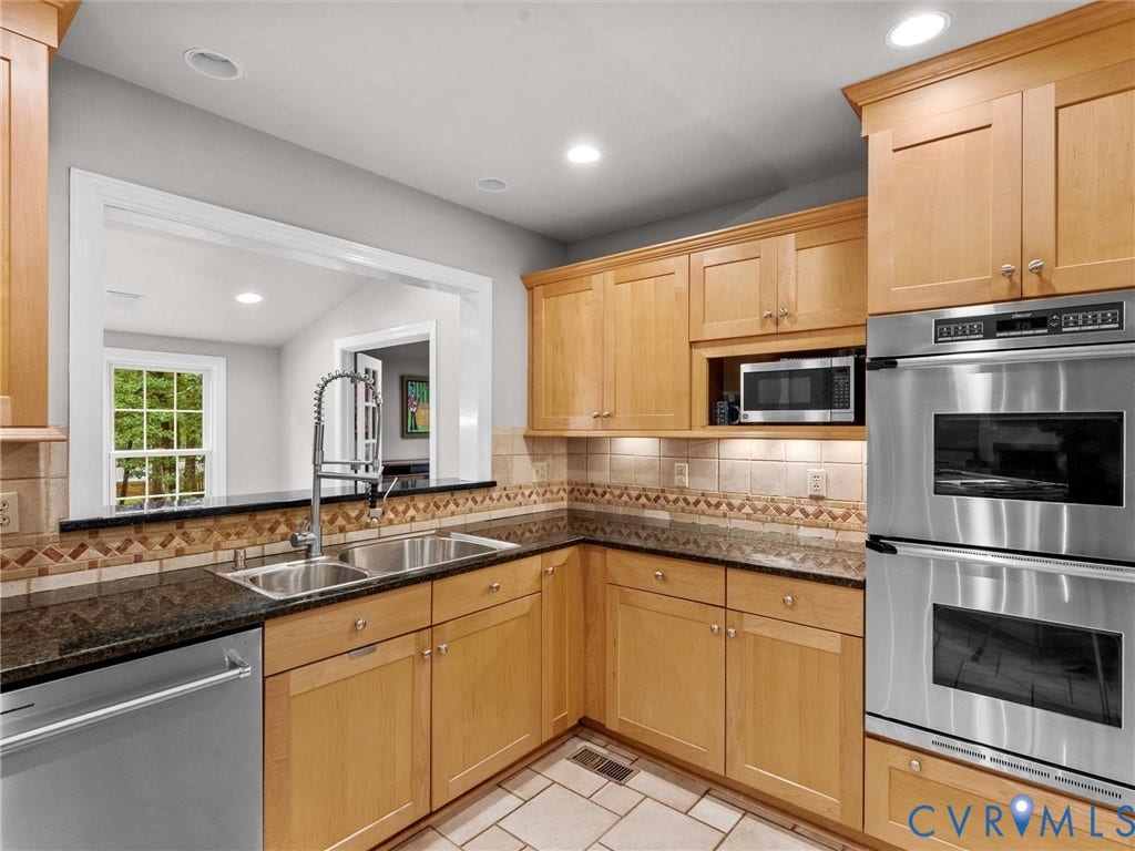 12100 English Ivy Lane, Glen Allen, VA 23059 Kitchen featuring light wood cabinetry, dark stone countertops, stainless steel double wall ovens, a tile backsplash, and a gooseneck faucet
