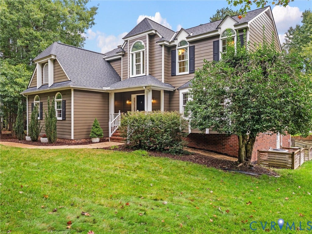 12100 English Ivy Lane, Glen Allen, VA 23059 Two-story residence featuring horizontal siding, brick masonry base, arched window detailing, multi-gabled roofline, and front porch with railings
