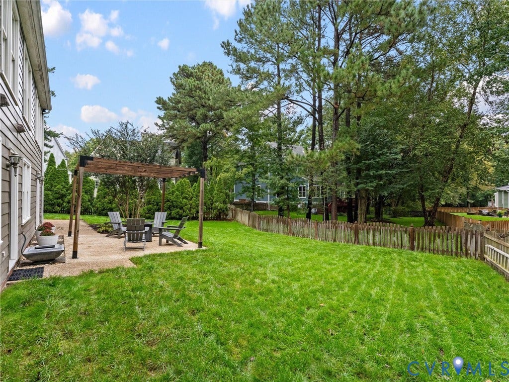 12100 English Ivy Lane, Glen Allen, VA 23059 Backyard featuring a paved patio with a wooden pergola, manicured lawn, perimeter fencing, and mature trees