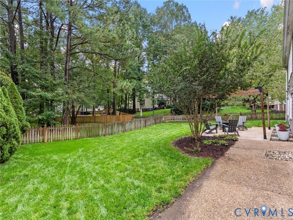 12100 English Ivy Lane, Glen Allen, VA 23059 Backyard featuring a concrete patio, a wooden pergola, a picket fence, and mature trees