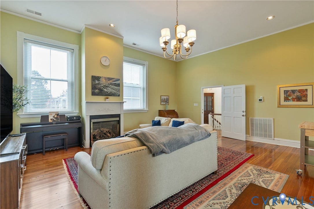 2021 North Avenue, Richmond, VA 23222 Hardwood flooring throughout, a gas fireplace with a white mantel, a multi-light chandelier, dual windows, and recessed lighting