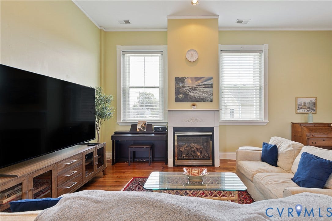 2021 North Avenue, Richmond, VA 23222 Hardwood flooring, gas fireplace with white mantel, two windows with blinds, recessed lighting, and crown molding