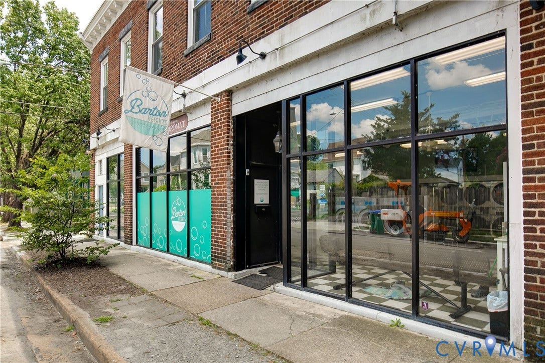 2021 North Avenue, Richmond, VA 23222 Brick facade building featuring multiple storefront windows, a pedestrian sidewalk, and a prominent commercial entrance