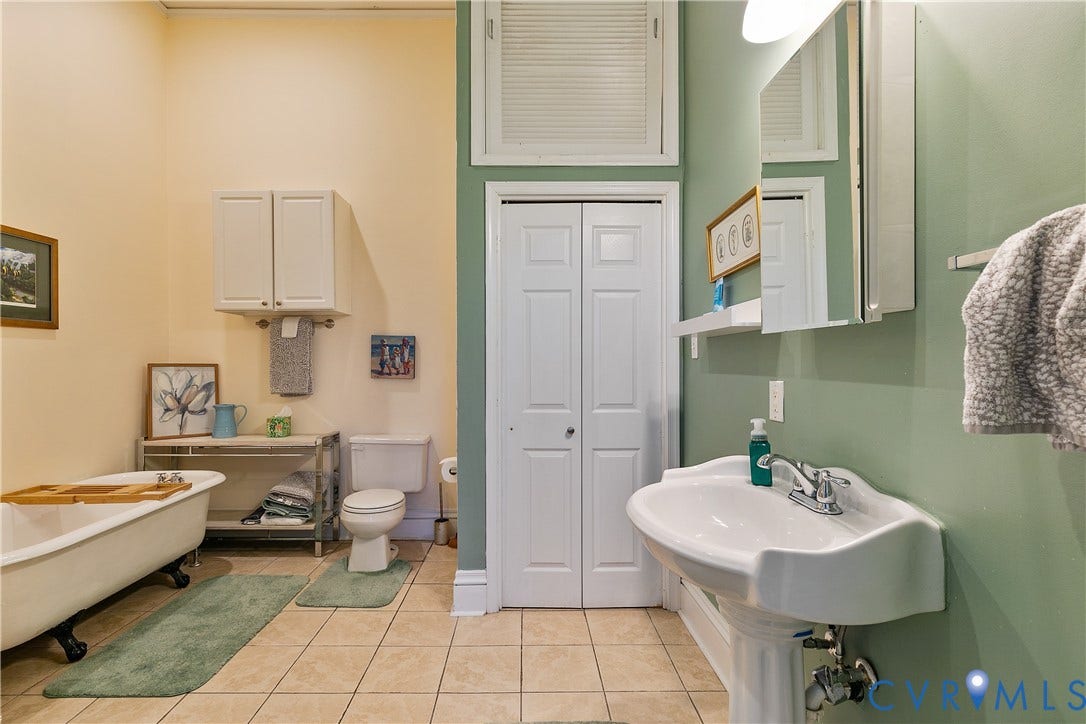 2021 North Avenue, Richmond, VA 23222 Pedestal sink with chrome fixtures, tiled flooring, built-in medicine cabinet, and a freestanding clawfoot tub