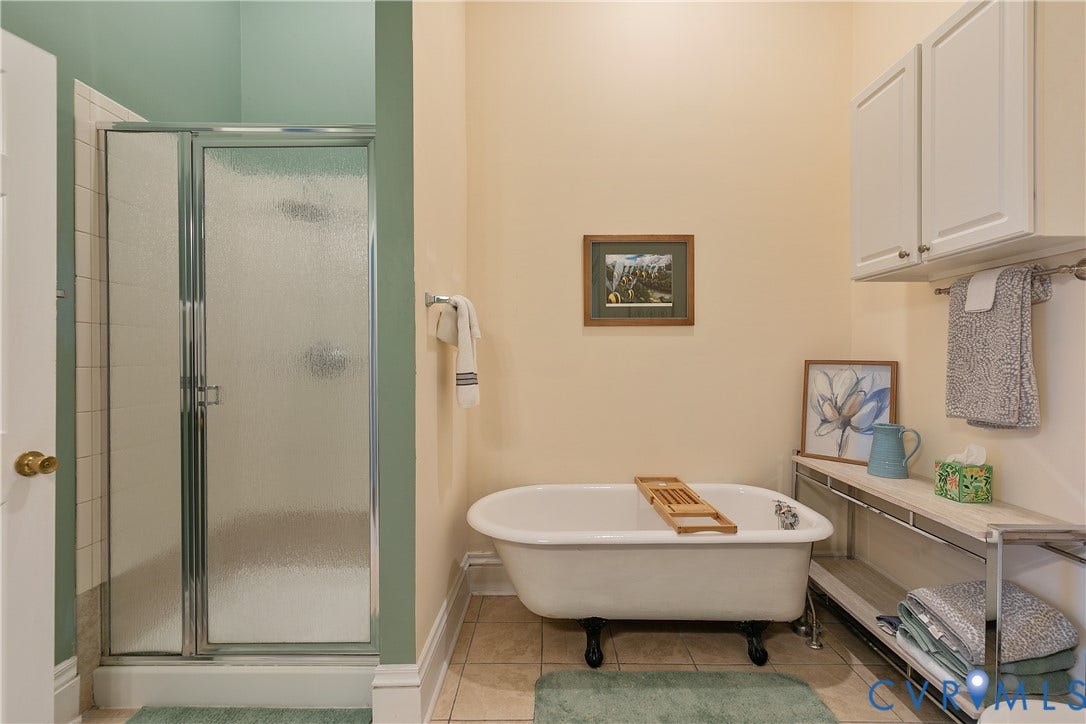 2021 North Avenue, Richmond, VA 23222 Clawfoot soaking tub, glass-enclosed shower, tile flooring, white cabinetry, and built-in shelving