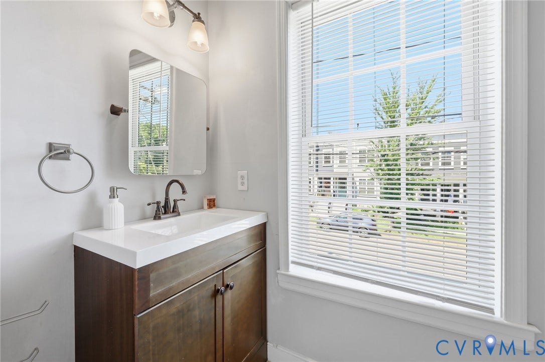 3015 M Street, Church Hill, Richmond, VA 23223 Single-sink vanity with white countertop, dark wood-finish cabinetry, rectangular mirror, and updated light fixture