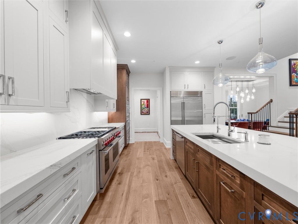 511 Libbie Avenue, #A, The Row At Westhampton, Richmond, VA 23226 Gourmet kitchen with wood-finish flooring, white cabinetry, stainless steel appliances, a center island with sink, and pendant lighting