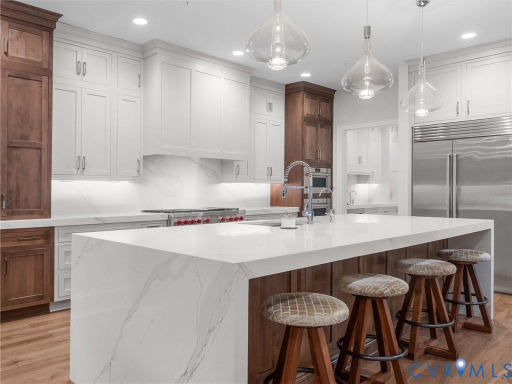 511 Libbie Avenue, #A, The Row At Westhampton, Richmond, VA 23226 Gourmet kitchen with a large waterfall island, white cabinetry, integrated stainless steel appliances, wood-finish flooring, and pendant lighting