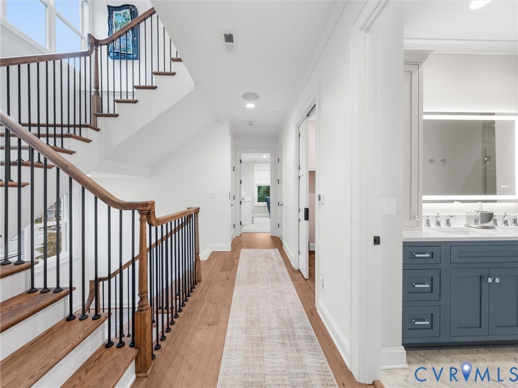 511 Libbie Avenue, #A, The Row At Westhampton, Richmond, VA 23226 Hardwood flooring throughout, a grand staircase with wood newel posts and black iron balusters, recessed lighting, and a double vanity with a marble countertop and illuminated mirror