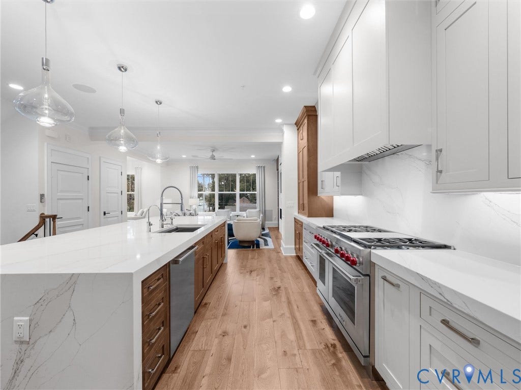 511 Libbie Avenue, #A, The Row At Westhampton, Richmond, VA 23226 Gourmet kitchen with wood-finish flooring, white cabinetry, a large center island with a sink, stainless steel appliances, and quartz countertops