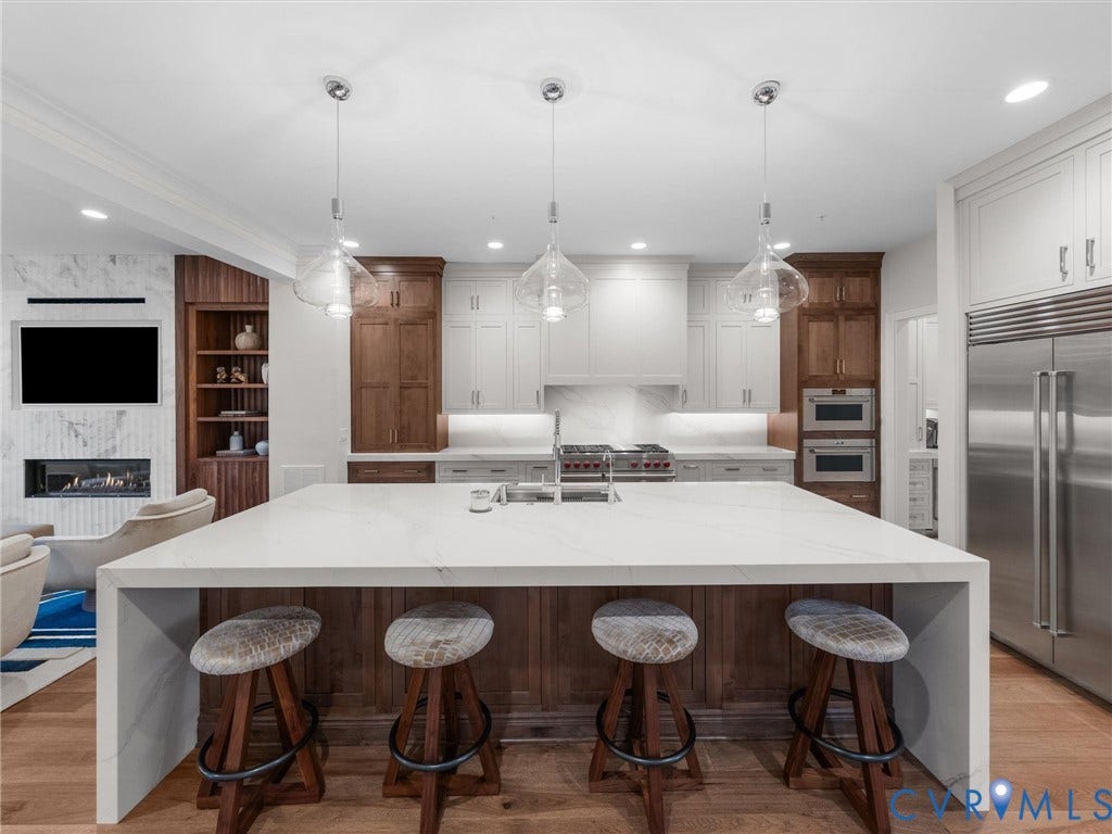 511 Libbie Avenue, #A, The Row At Westhampton, Richmond, VA 23226 Waterfall island with a white countertop and wood-finish base, stainless steel appliances, wood-finish flooring, two-tone cabinetry, and a marble-clad fireplace