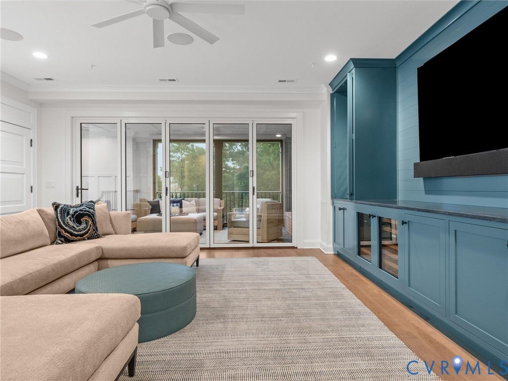 511 Libbie Avenue, #A, The Row At Westhampton, Richmond, VA 23226 Expansive multi-panel sliding glass doors, built-in media cabinetry with glass-front storage, recessed lighting, wood-finish flooring, and a ceiling fan