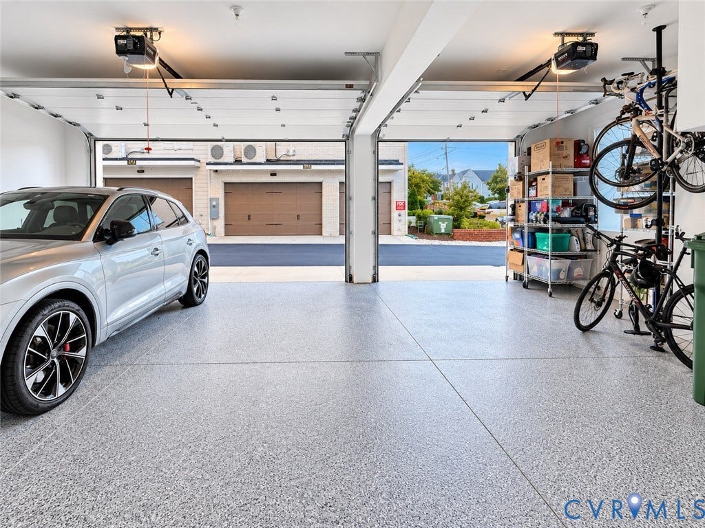 511 Libbie Avenue, #A, The Row At Westhampton, Richmond, VA 23226 Spacious epoxy-coated garage with polished concrete flooring, overhead storage racks, wall-mounted bike storage, and abundant natural light from dual garage doors