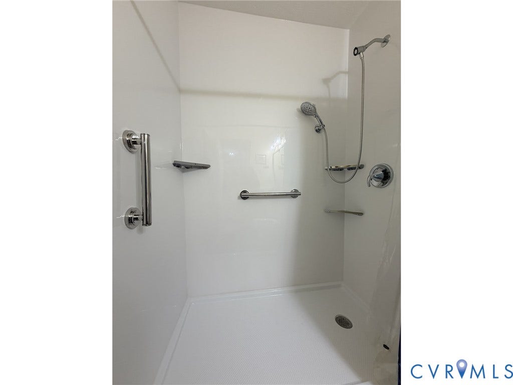 5325 Swift Hill Lane, Scandia Lake, Sandston, VA 23150 Shower enclosure with white panel walls, chrome grab bars, and a handheld shower fixture