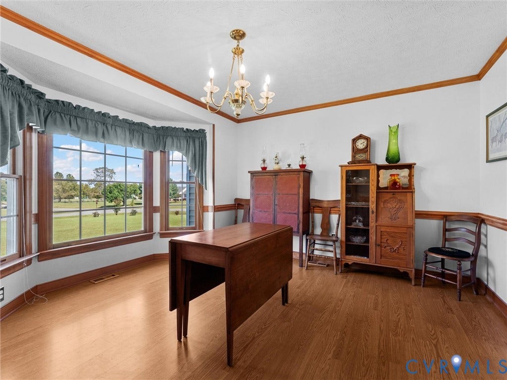 5325 Swift Hill Lane, Scandia Lake, Sandston, VA 23150 Bay window with wood trim, wood-finish flooring, decorative chair rail, crown molding, and a chandelier