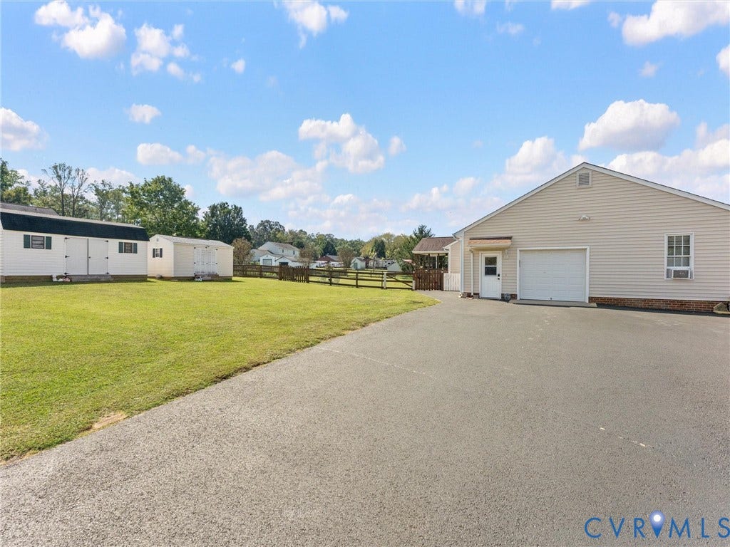 5325 Swift Hill Lane, Scandia Lake, Sandston, VA 23150 Paved driveway, attached garage, side entry door, two storage sheds, and a wooden fence