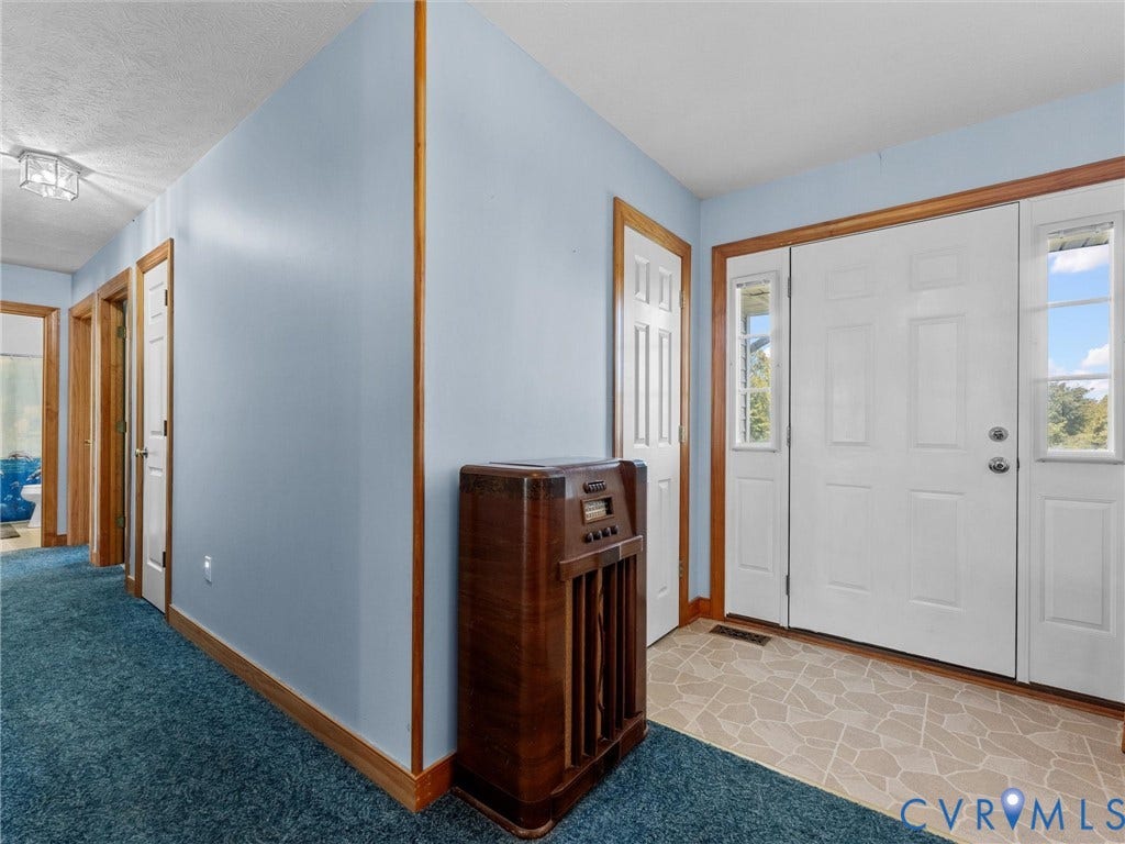 5325 Swift Hill Lane, Scandia Lake, Sandston, VA 23150 Entryway featuring a white paneled front door, two sidelight windows, light-toned patterned tile flooring, and wood trim details