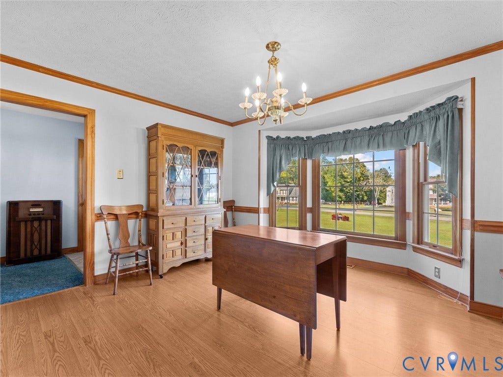 5325 Swift Hill Lane, Scandia Lake, Sandston, VA 23150 Wood-finish flooring, bay window, gold-toned chandelier, white walls, and wood trim throughout
