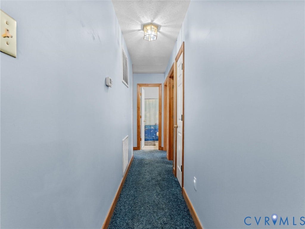 5325 Swift Hill Lane, Scandia Lake, Sandston, VA 23150 Hallway with blue wall finishes, blue carpeting, and wood-finish door frames