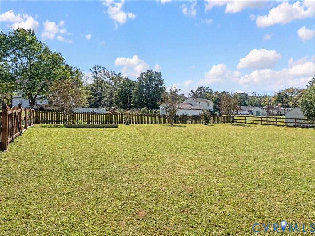 5325 Swift Hill Lane, Scandia Lake, Sandston, VA 23150 Expansive grassy lawn with a wood picket fence and a raised garden bed