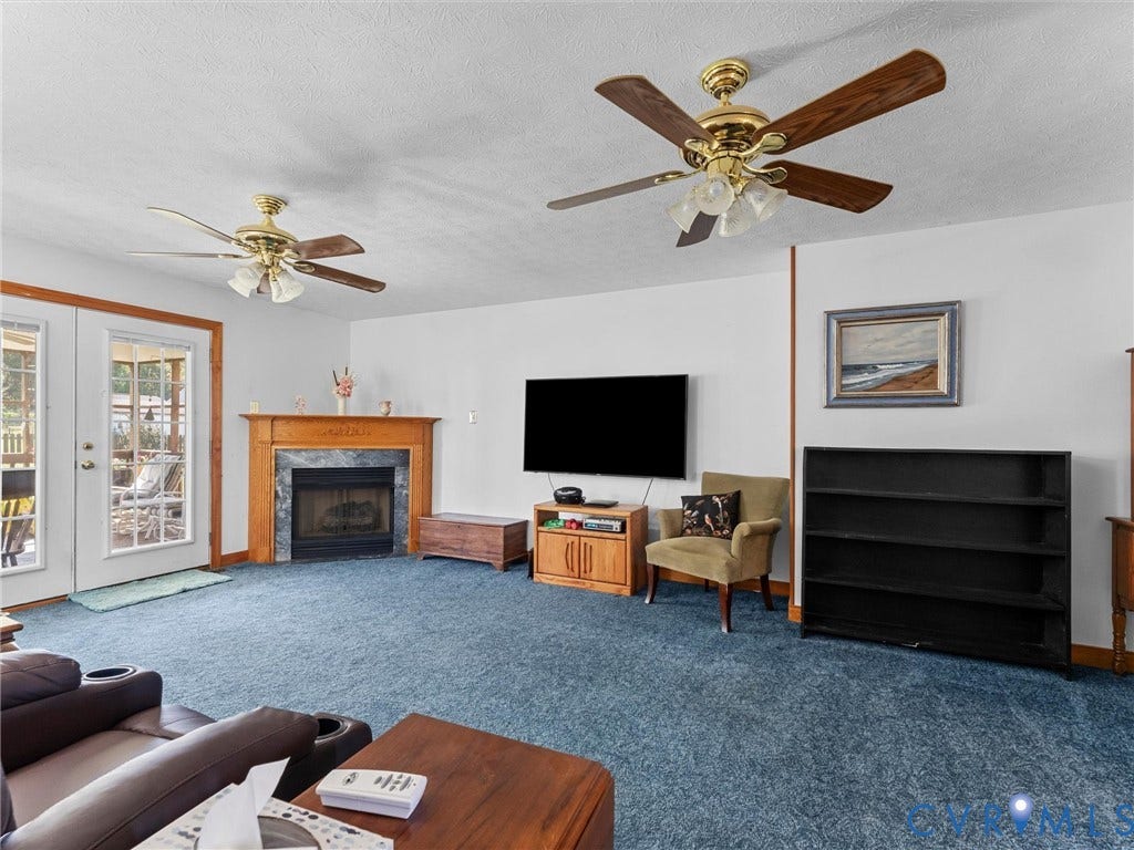 5325 Swift Hill Lane, Scandia Lake, Sandston, VA 23150 Living area featuring a fireplace with a wood mantle, dual ceiling fans, and double glass-paneled doors