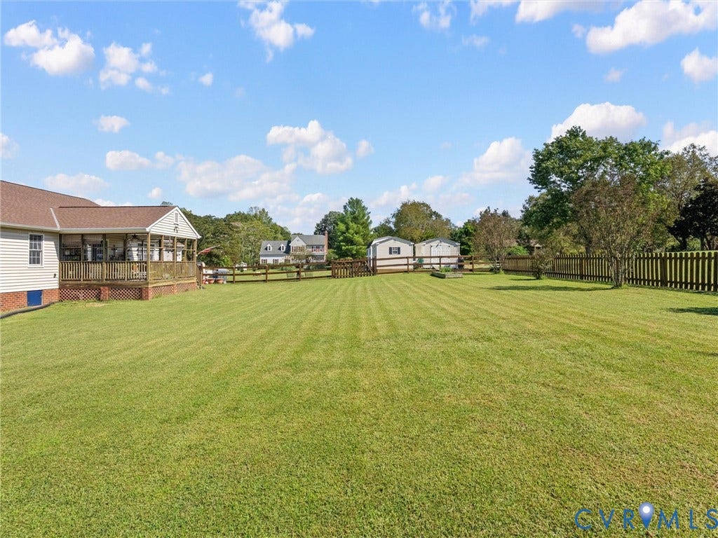 5325 Swift Hill Lane, Scandia Lake, Sandston, VA 23150 Expansive green lawn with a wood plank fence and two storage sheds