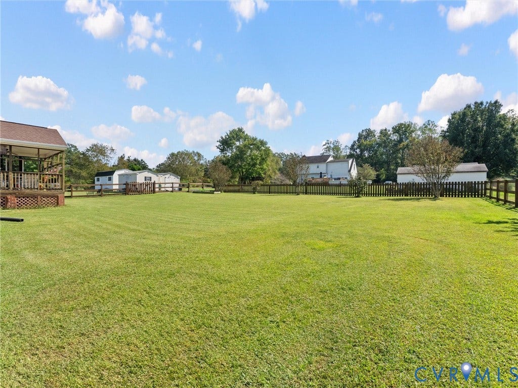5325 Swift Hill Lane, Scandia Lake, Sandston, VA 23150 Expansive green lawn with a wood plank fence and a partial covered porch featuring wood railings