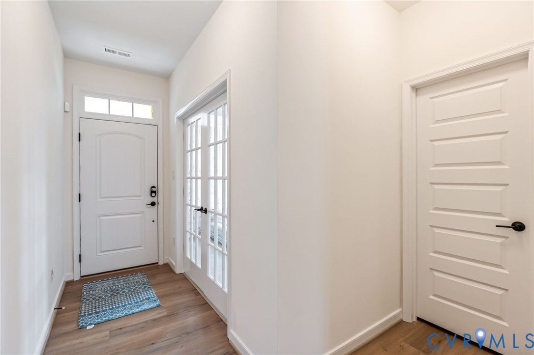 Entryway featuring wood-finish flooring, white walls, and a transom window above the main door
