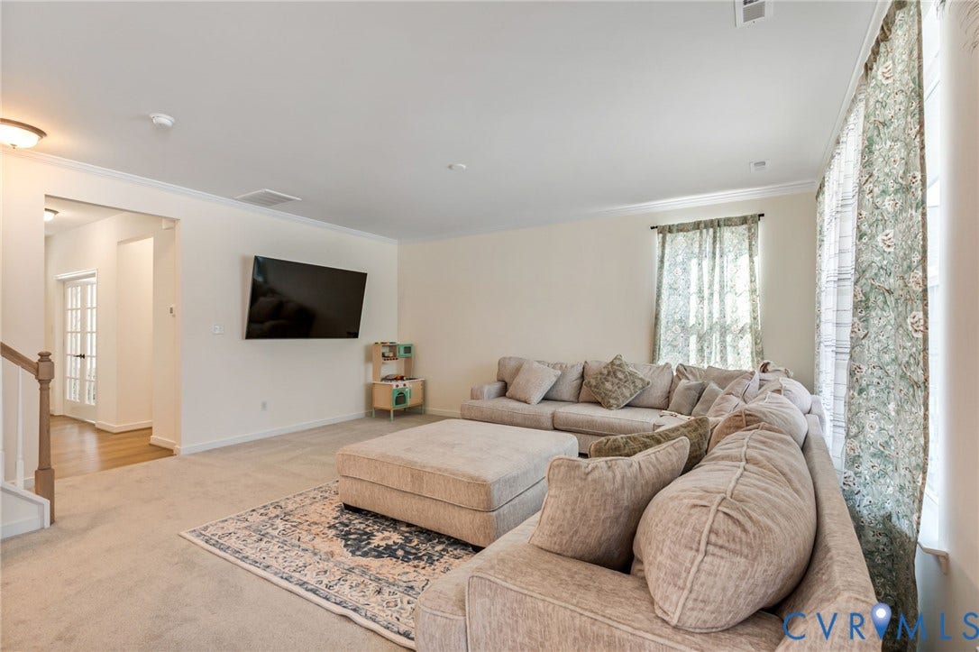 Spacious living area featuring neutral-toned walls, crown molding, and recessed lighting