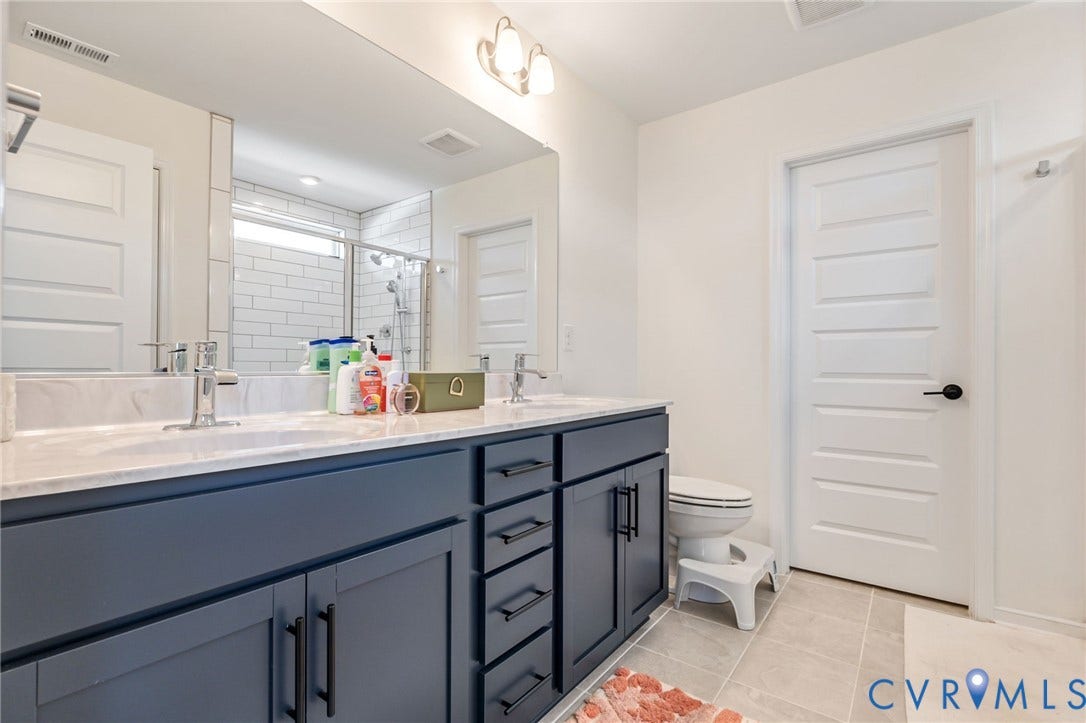 Dual vanity with undermount sinks, stone-finish countertop, dark wood-finish cabinetry, and contemporary silver-tone faucets
