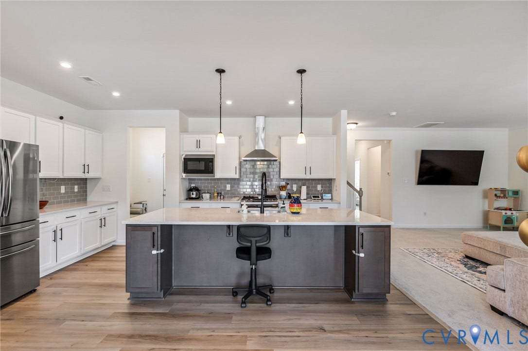 Modern kitchen featuring white cabinetry, stainless steel appliances, a large island with contrasting base cabinetry, and wood-finish flooring