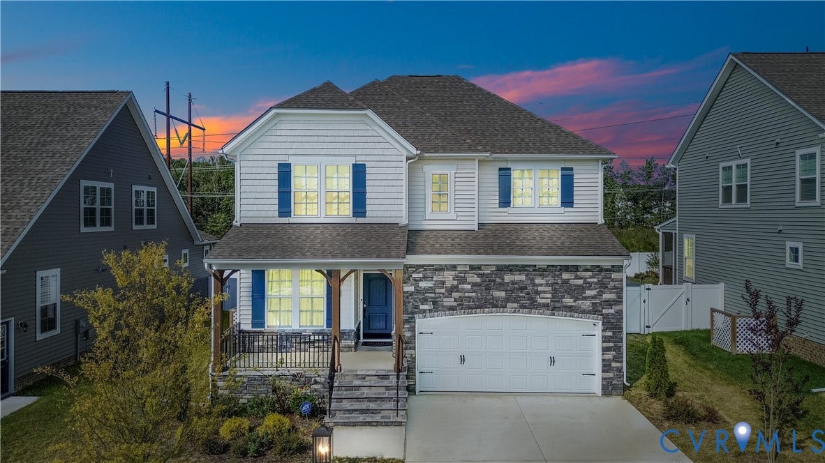 Two-story residence featuring a covered front porch, stone and siding exterior, attached garage, and paved driveway