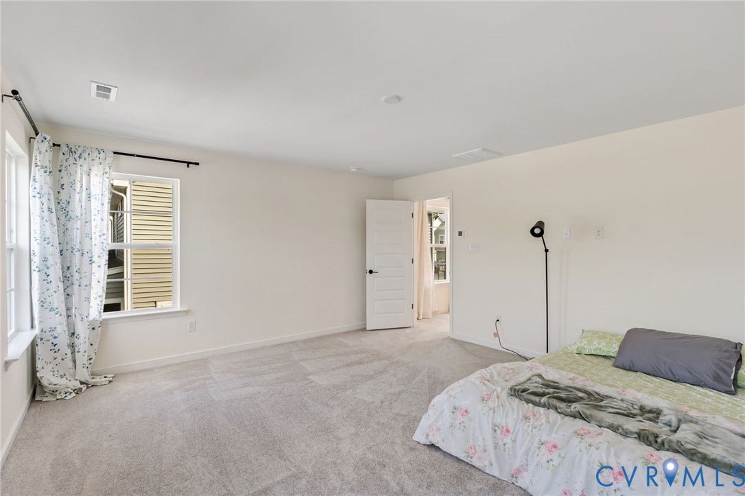 Neutral wall paint, light gray carpet, multiple windows, white paneled door with black hardware, recessed ceiling lighting