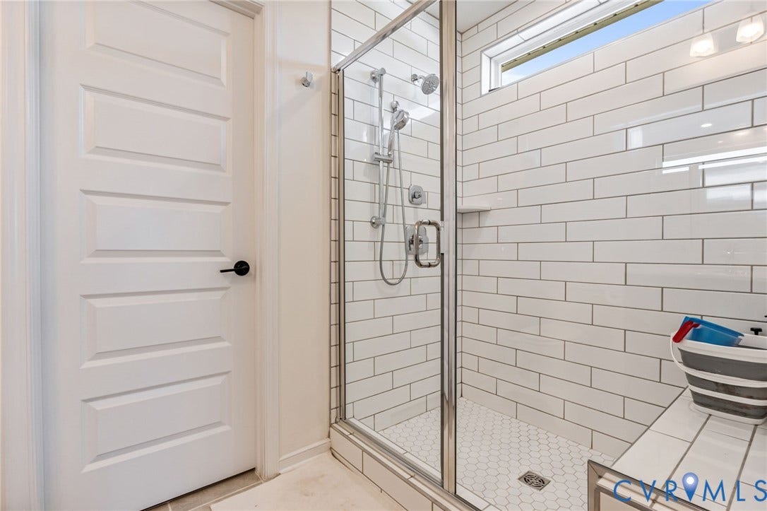 Glass-enclosed shower with subway tile surround, hexagon tile flooring, built-in bench, and an upper transom window